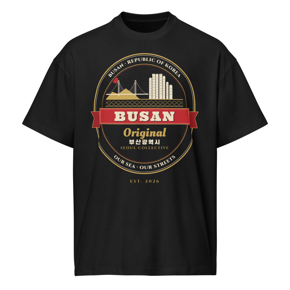 Busan Emblem Tee, front: a gold-and-red Busan crest with Haeundae towers and Gwangan Bridge on a black oversized tee